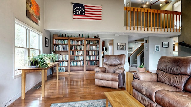 living room with visible vents, stairs, wood finished floors, baseboards, and a high ceiling