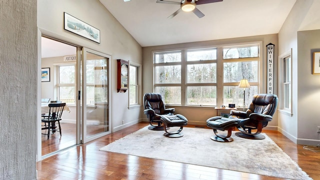 living area featuring baseboards, a ceiling fan, wood finished floors, and high vaulted ceiling