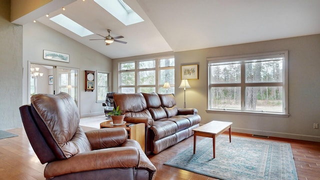 living area with baseboards, wood finished floors, visible vents, and a skylight