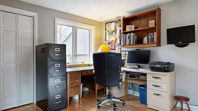 office space with a textured ceiling, a baseboard radiator, and light wood-style floors