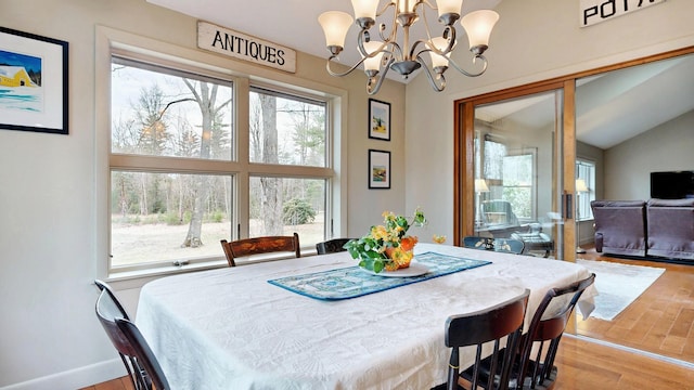 dining room featuring baseboards, wood finished floors, a chandelier, and vaulted ceiling