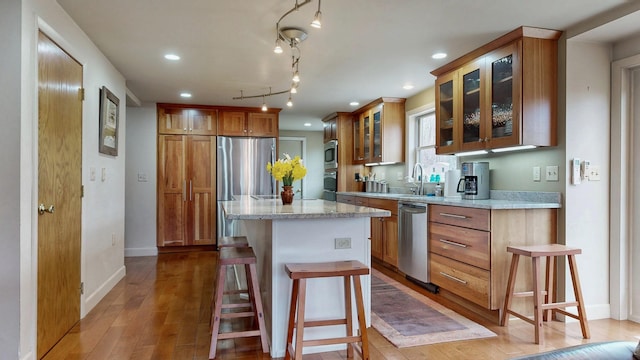 kitchen featuring a kitchen island, appliances with stainless steel finishes, brown cabinets, light wood-style floors, and recessed lighting