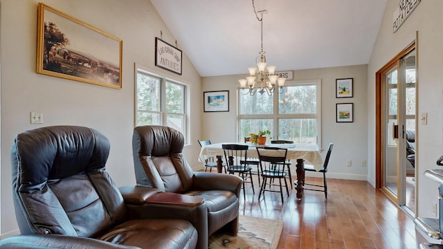 dining room featuring baseboards, an inviting chandelier, light wood-style flooring, and high vaulted ceiling