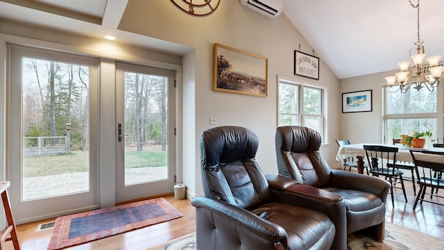living area featuring an inviting chandelier, visible vents, high vaulted ceiling, a wall unit AC, and light wood finished floors