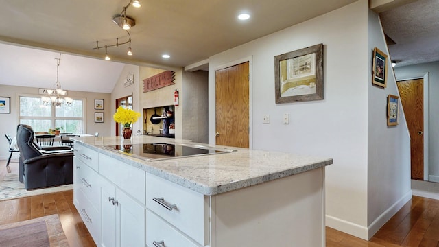 kitchen featuring a kitchen island, light wood-type flooring, baseboards, white cabinets, and black electric stovetop