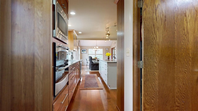 kitchen with light countertops, stainless steel appliances, brown cabinets, and dark wood-type flooring