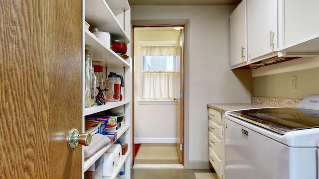 laundry area featuring baseboards, washer / dryer, cabinet space, and light tile patterned floors