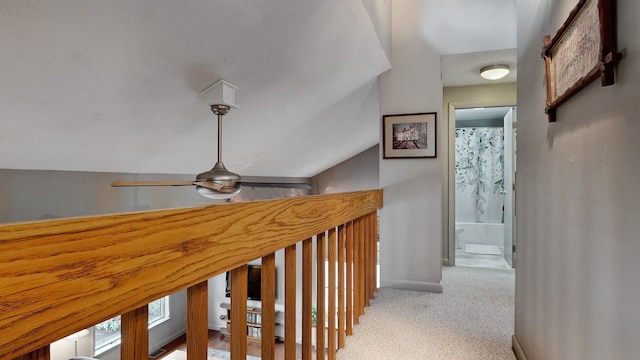 hall featuring baseboards, light colored carpet, and lofted ceiling