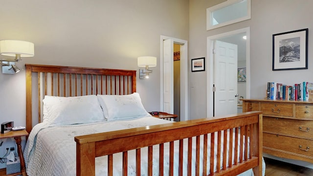 bedroom with wood finished floors and a towering ceiling