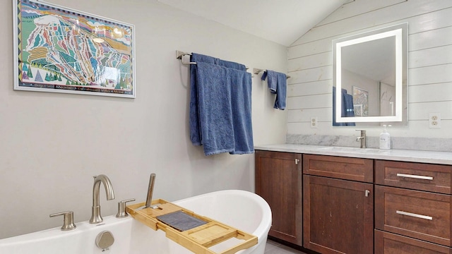 bathroom with wooden walls, a freestanding tub, lofted ceiling, and vanity