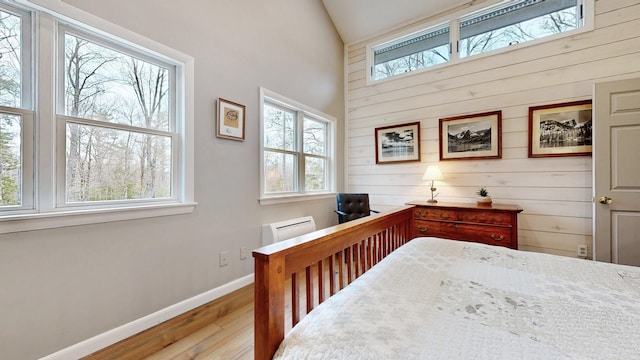 bedroom featuring multiple windows, wood walls, and wood finished floors