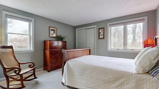 bedroom featuring baseboards, light colored carpet, and a closet