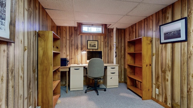 carpeted office space with wooden walls and a drop ceiling
