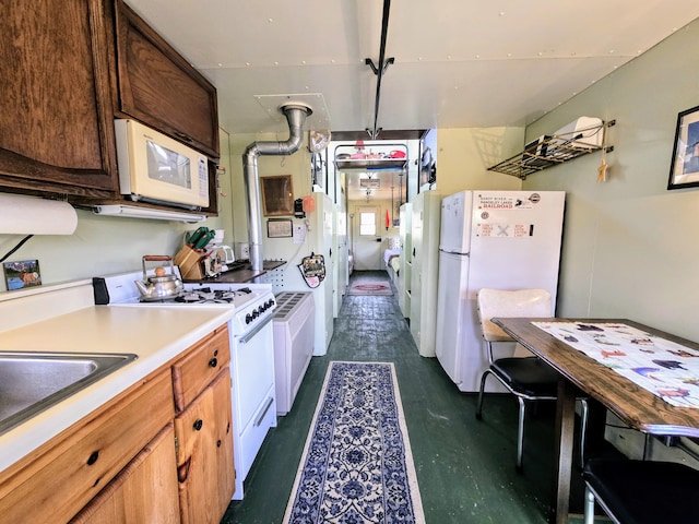 kitchen featuring light countertops, white appliances, and a sink