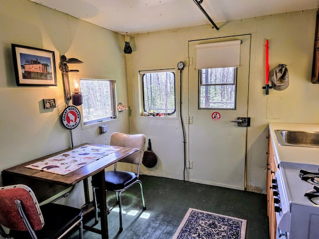 interior space featuring white gas range, baseboards, and a sink