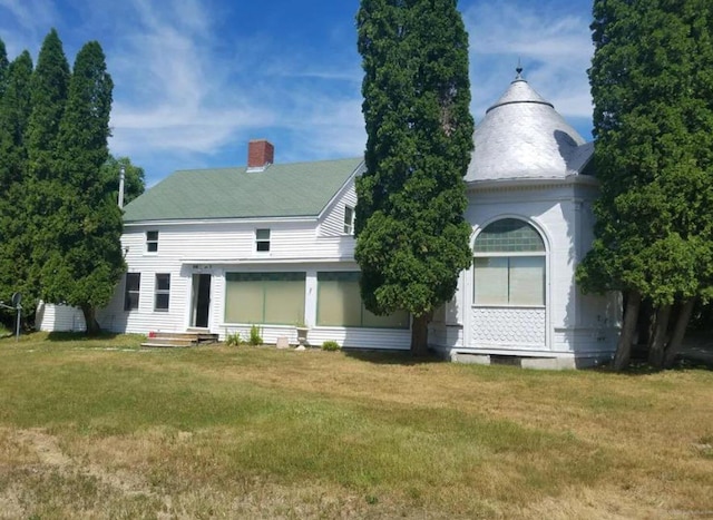 back of house with a yard and a chimney