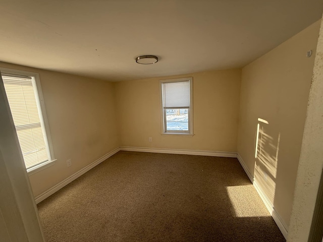 empty room featuring baseboards and dark colored carpet