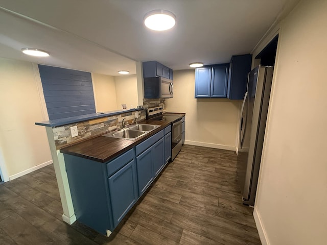kitchen featuring stainless steel appliances, blue cabinetry, a sink, and a peninsula