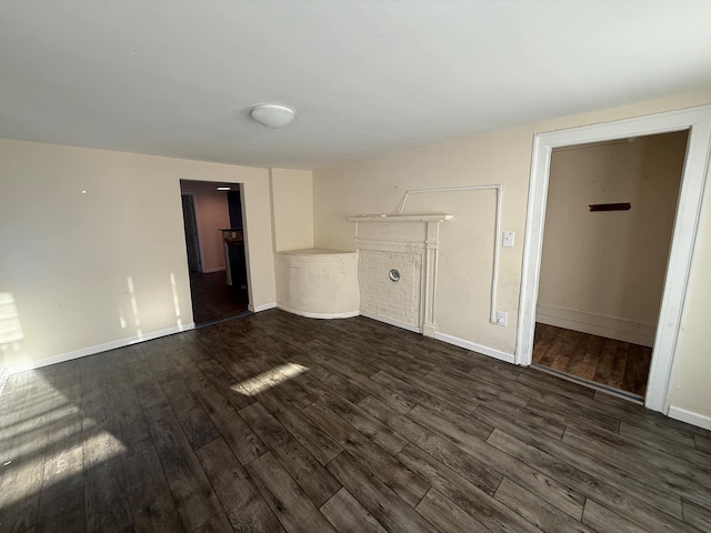 unfurnished living room with baseboards and dark wood-style floors
