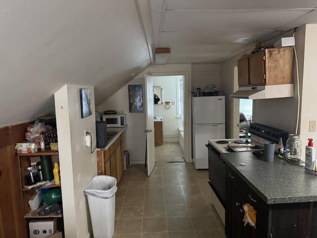kitchen featuring dark countertops, tile patterned flooring, lofted ceiling, under cabinet range hood, and white appliances