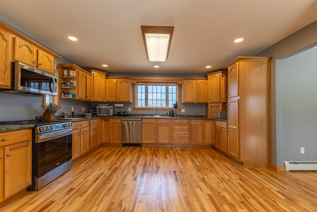 kitchen with brown cabinetry, appliances with stainless steel finishes, a baseboard heating unit, light wood-style floors, and recessed lighting