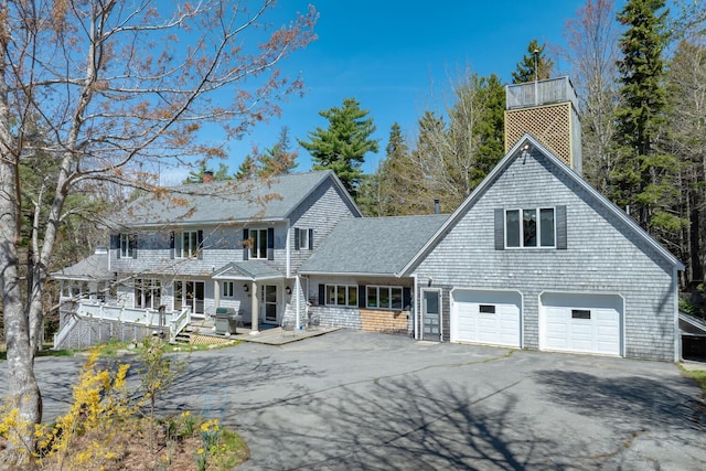 20 Giant Slide Rd, Mount Desert, ME 04660 - view of front facade with a chimney, asphalt driveway, a porch, an attached garage, and roof with shingles