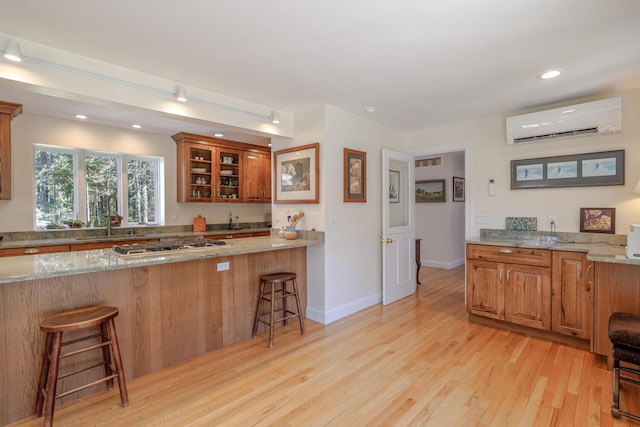 20 Giant Slide Rd, Mount Desert, ME 04660 - kitchen featuring a wall unit AC, a sink, a breakfast bar, light wood-style flooring, and light stone countertops