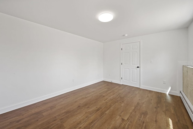 empty room with baseboards, dark wood finished floors, and a baseboard heating unit