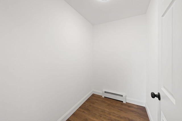 spare room with baseboards, a baseboard heating unit, and dark wood-type flooring