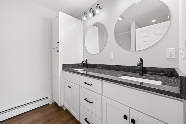 bathroom with double vanity, a sink, baseboard heating, and wood finished floors