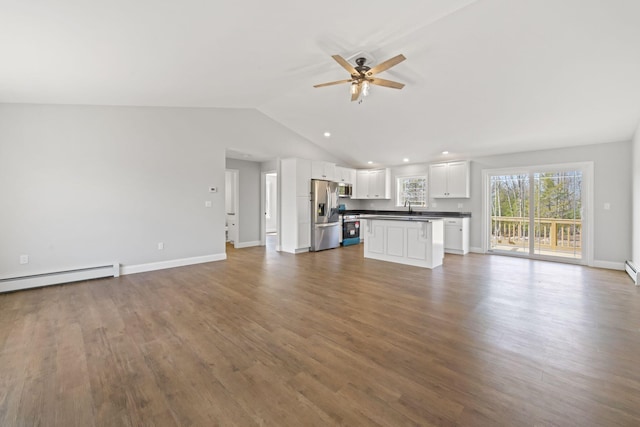 unfurnished living room with a sink, a baseboard radiator, dark wood-type flooring, a ceiling fan, and vaulted ceiling
