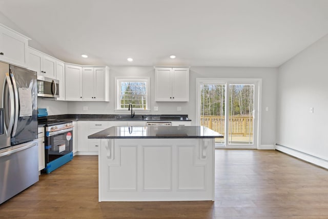 kitchen with a sink, appliances with stainless steel finishes, white cabinets, and dark countertops