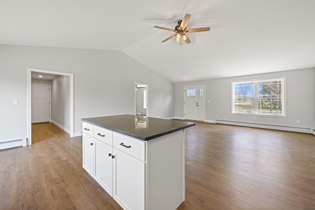 kitchen with a ceiling fan, wood finished floors, a kitchen island, lofted ceiling, and a baseboard radiator