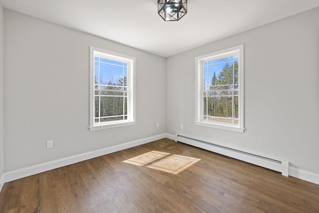 spare room featuring baseboards, baseboard heating, and wood finished floors