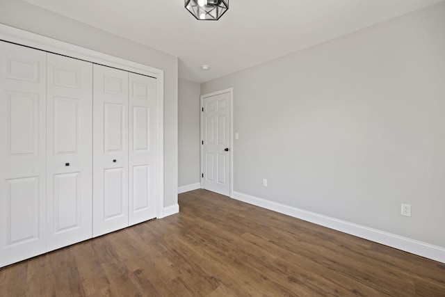 unfurnished bedroom with baseboards, a closet, and wood finished floors
