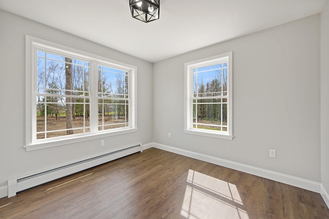 unfurnished room with baseboards, plenty of natural light, baseboard heating, and wood finished floors