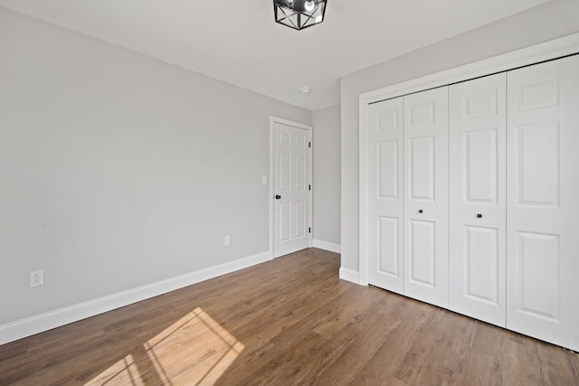 unfurnished bedroom with baseboards, wood finished floors, and a closet