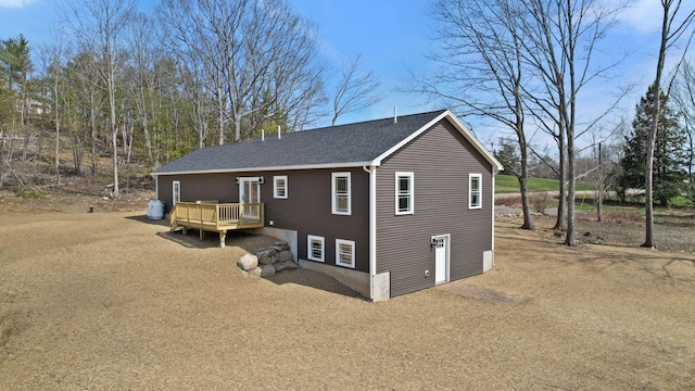 view of side of property featuring a wooden deck and a shingled roof