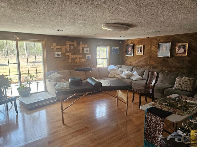 living room featuring a textured ceiling, wood finished floors, and wooden walls