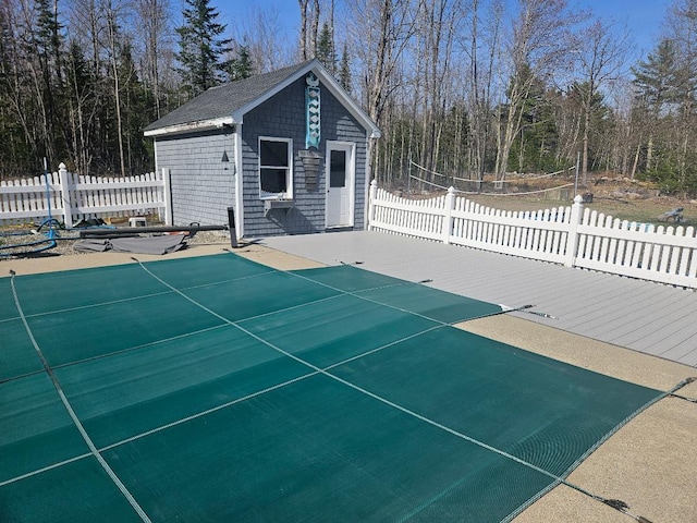 view of swimming pool featuring fence and an outbuilding