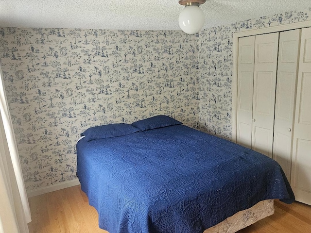 193 N Rd, Detroit, ME 04929 - bedroom with wallpapered walls, wood finished floors, a textured ceiling, and a closet