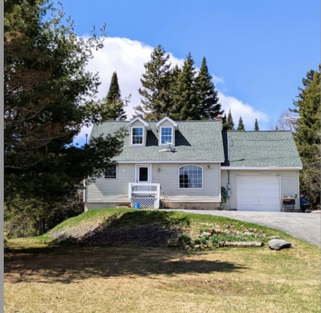 cape cod-style house with an attached garage, a front lawn, and aphalt driveway