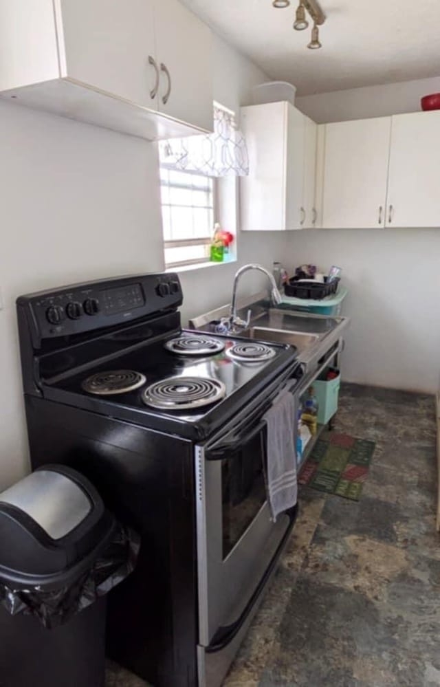 kitchen featuring a sink, electric range, and white cabinets