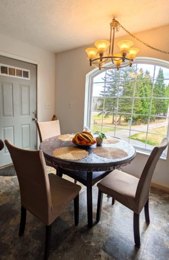 dining area featuring an inviting chandelier, plenty of natural light, and a textured ceiling