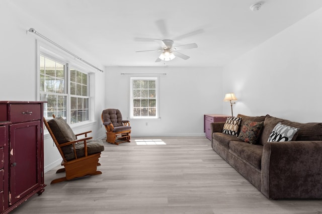 living area with light wood-style floors, baseboards, and a ceiling fan