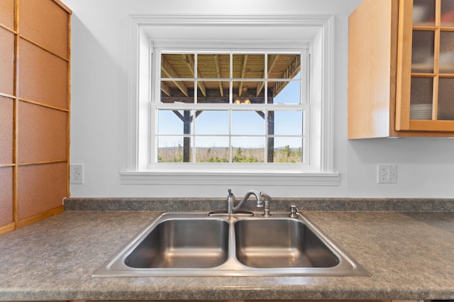 details with a sink, dark countertops, and glass insert cabinets