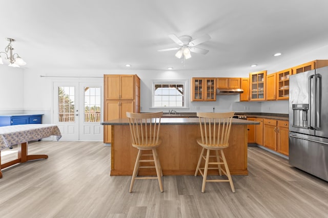 kitchen featuring a center island, light wood-style floors, under cabinet range hood, and stainless steel fridge with ice dispenser