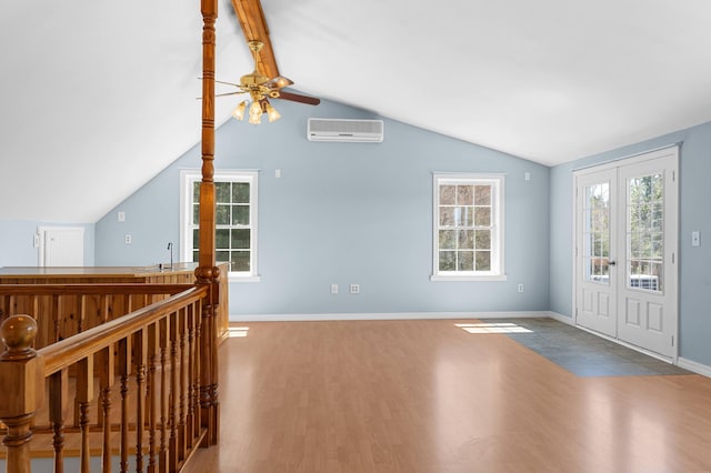foyer entrance featuring wood finished floors, baseboards, a wall unit AC, a ceiling fan, and vaulted ceiling