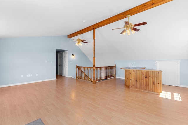 unfurnished living room featuring baseboards, ceiling fan, vaulted ceiling with beams, a sink, and light wood-style flooring