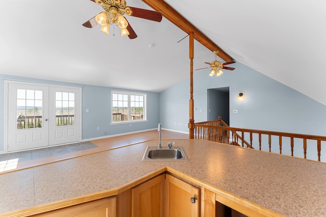 kitchen featuring ceiling fan, a sink, light countertops, open floor plan, and vaulted ceiling with beams